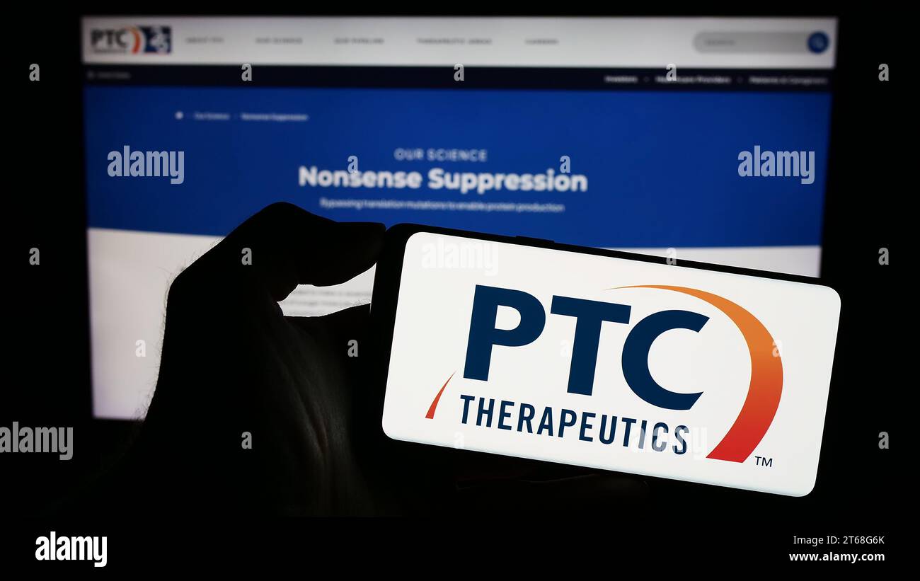 Person, die ein Mobiltelefon mit dem Logo des US-Pharmaunternehmens PTC Therapeutics Inc. Vor der Website des Unternehmens hält. Schwerpunkt auf dem Display des Telefons. Stockfoto