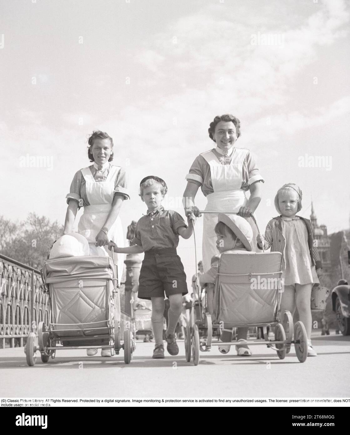 Für einen Spaziergang in den 1940ern Zwei Frauen in Krankenschwestern-Uniform laufen draußen und schieben Kinderwagen vor ihnen hinein. Stockholm Schweden Mai 1940 Kristoffersson Ref. 133-6 Stockfoto