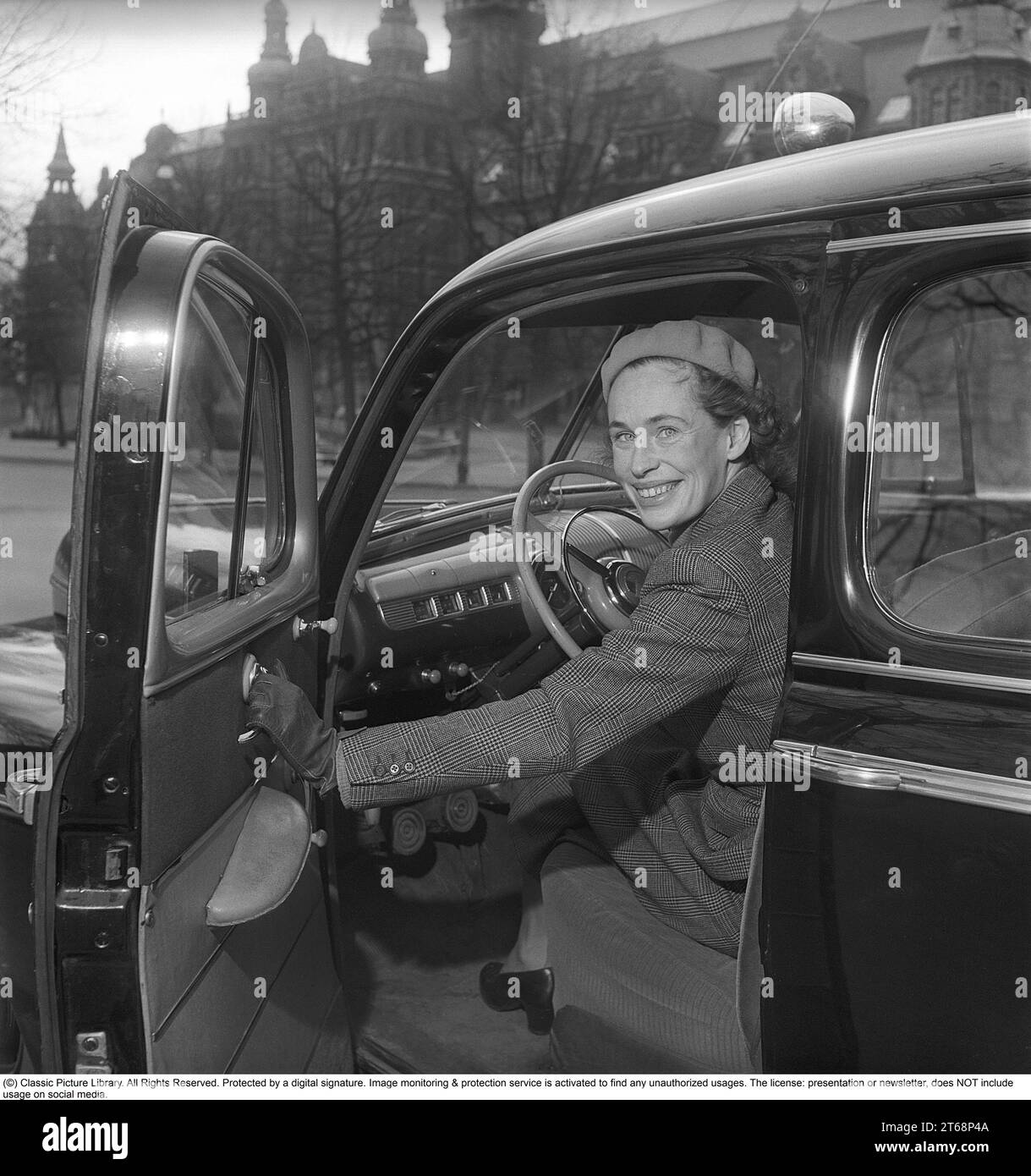 In den 1940er Jahren Eine junge Frau am Steuer ihres Autos der amerikanischen Automobilmarke Ford. Sie trägt einen zweiteiligen Anzug, einen Rock und eine kurze Jacke aus Fischgrätwolle. Das Foto wurde 1949 in Stockholm, Schweden, aufgenommen. Kristoffersson Ref. AY83-12 Stockfoto