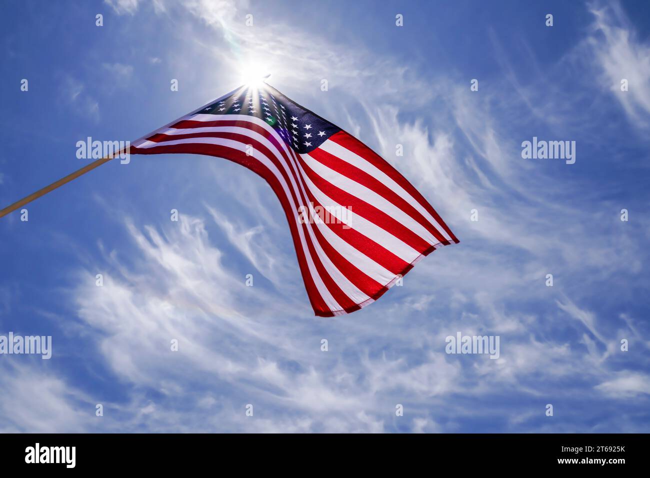 Die amerikanische Flagge winkt in einem blauen Himmel mit einer Sternenbewegung hinter der Flagge der USA. Der rote, weiße und blaue Stern stieß die US-Flagge hoch. Stockfoto