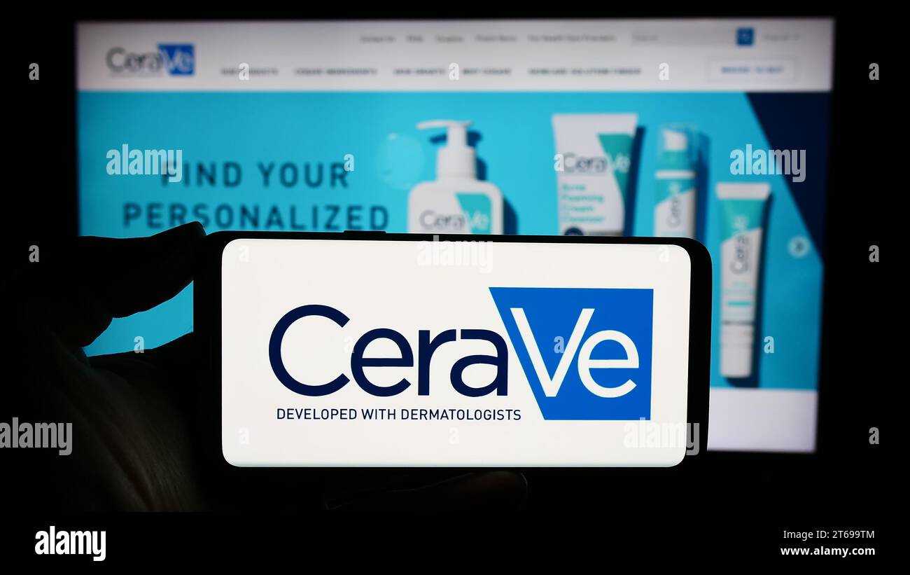 Person mit Smartphone und Logo des Körperpflegeunternehmens CeraVe (L’Oreal) vor der Website. Schwerpunkt auf dem Display des Telefons. Stockfoto