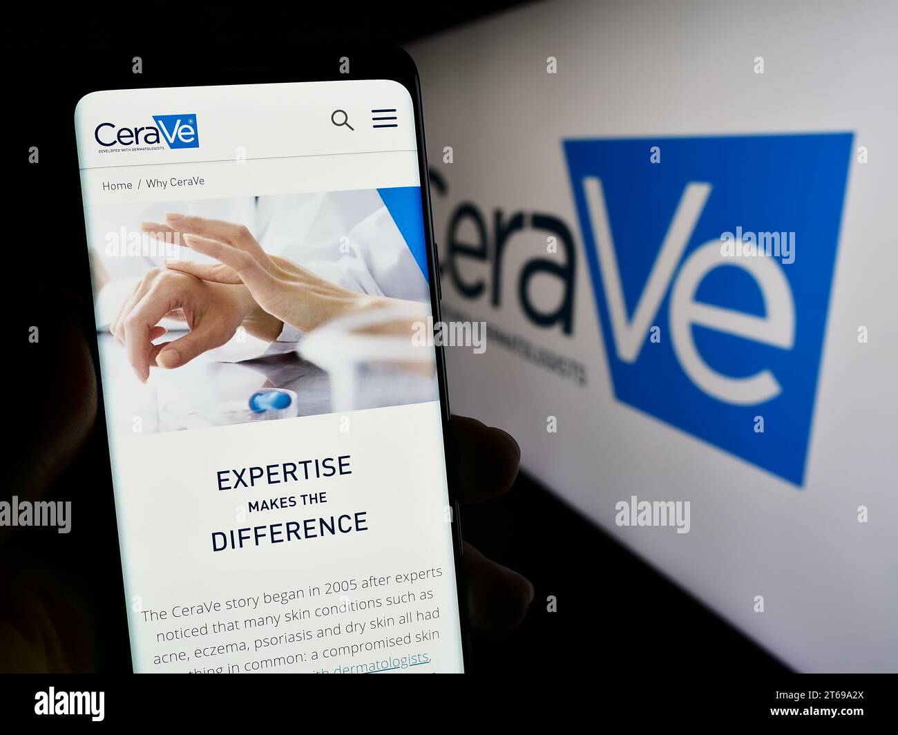 Person, die ein Mobiltelefon hält, mit der Webseite des Körperpflegeunternehmens CeraVe (L’Oreal) vor dem Firmenlogo. Konzentrieren Sie sich auf die Mitte des Telefondisplays. Stockfoto