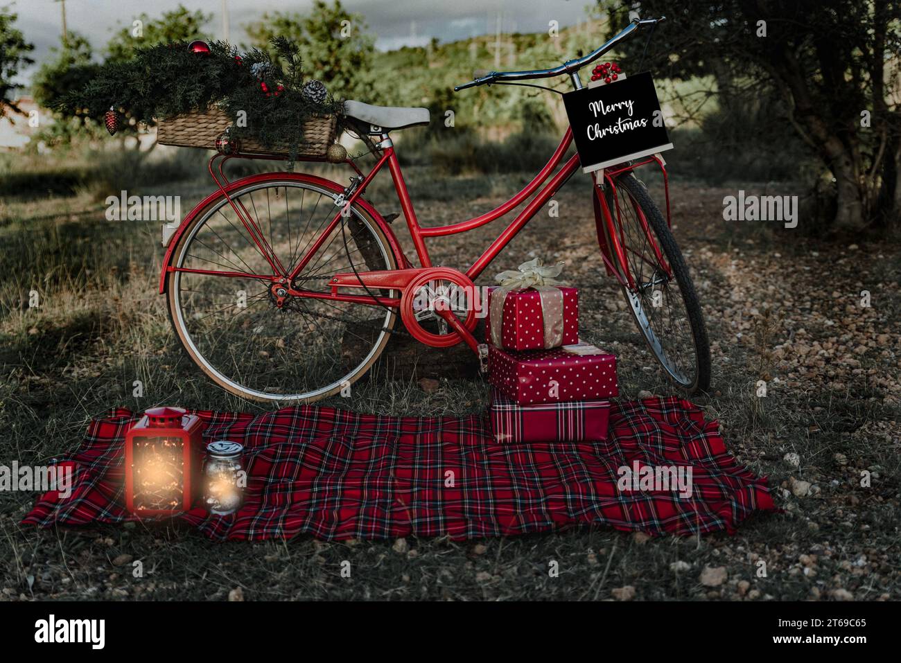 Rotes Fahrrad mit Weihnachtsgeschenken und ein paar Laternen im Freien. Stockfoto