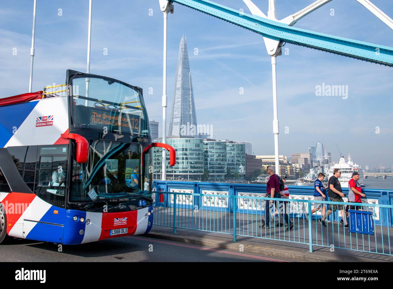 Ein Touristenbus fährt über die Tower Bridge in London zusammen mit einer Gruppe von Menschen, die im Hintergrund den Shard Wolkenkratzer sehen Stockfoto