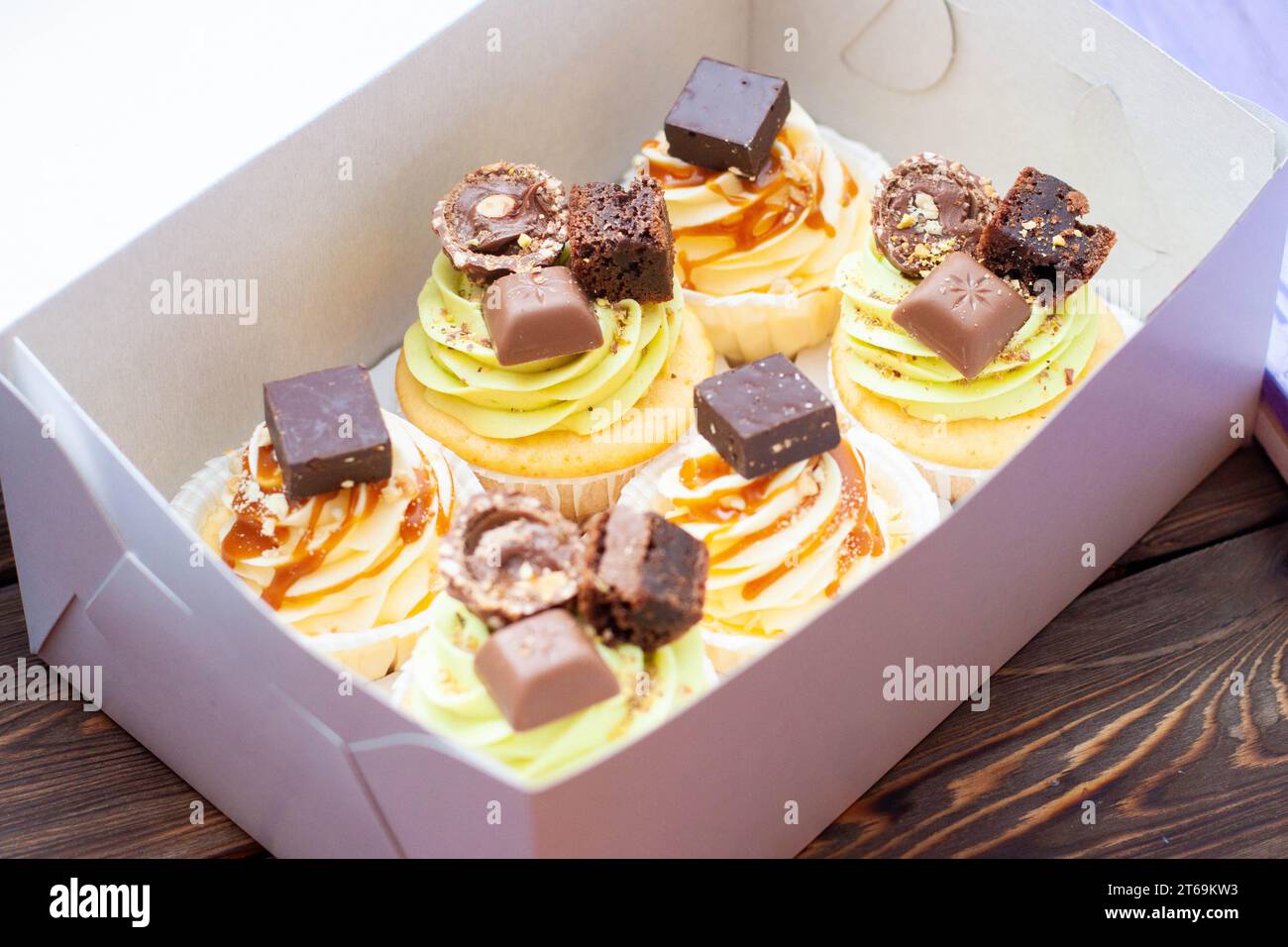 Gesalzene Karamell Pistaziencupcakes mit Sirup, Brezeln und Schokoladenbissen in einer Geschenkbox Stockfoto