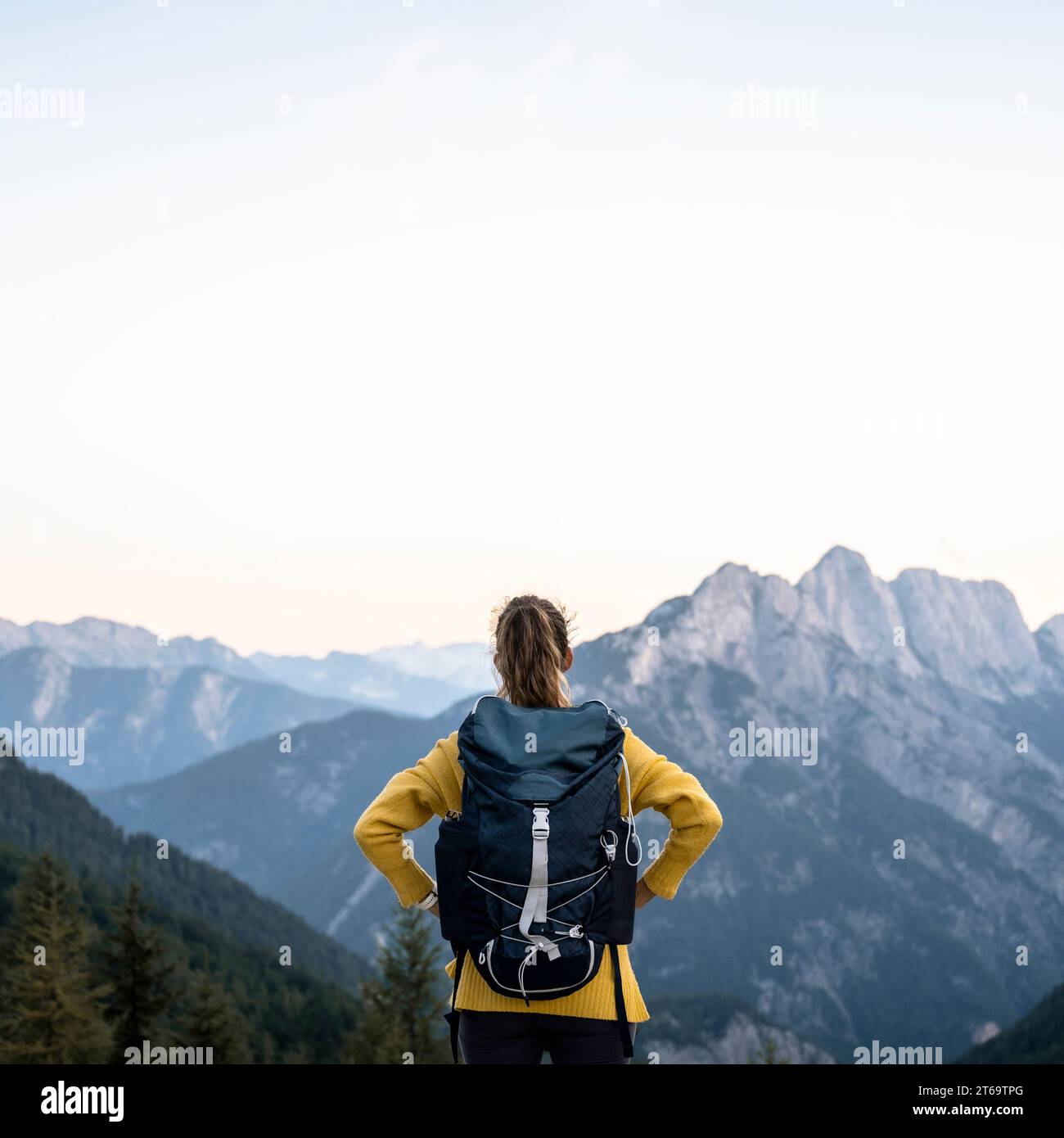 Blick von hinten auf eine Wanderer mit Rucksack auf einem Berg mit wunderschönem Blick auf andere hohe Gipfel. Unter klarem Himmel. Stockfoto