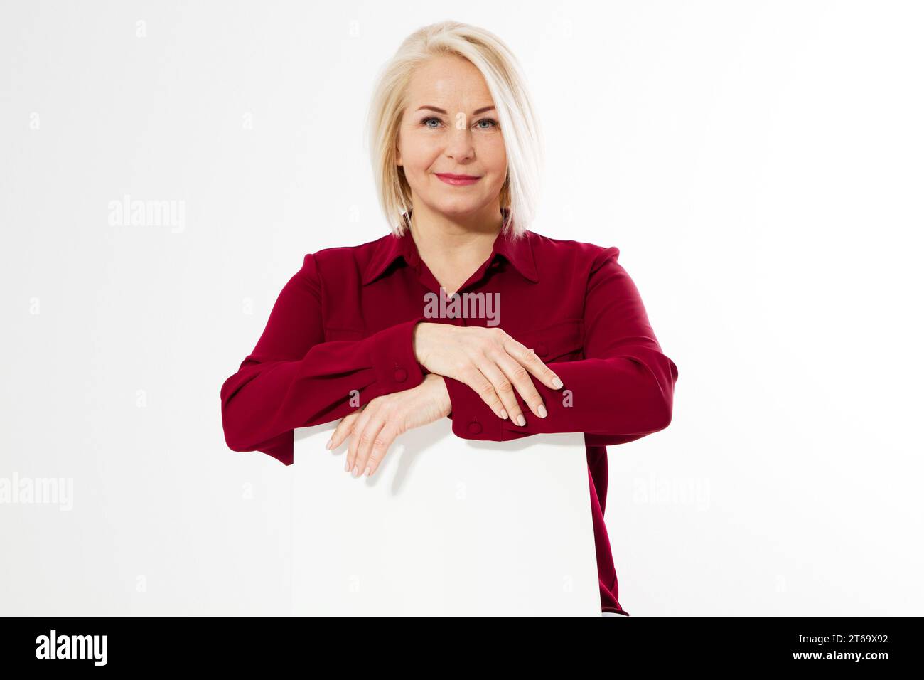 Eine Frau mittleren Alters sitzt auf einem Stuhl und lehnte ihre Arme auf die Rückseite eines Stuhls, weibliches Porträt mittleren Alters aus nächster Nähe Stockfoto