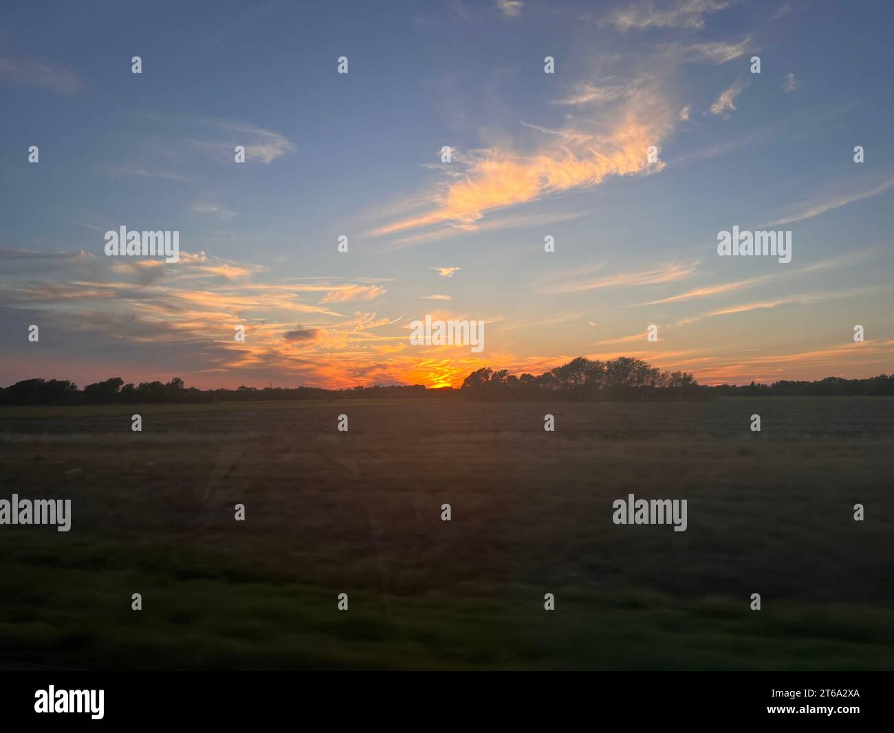 Ein idyllischer Sonnenuntergang auf einem offenen Feld, durch ein Zugfenster gesehen Stockfoto