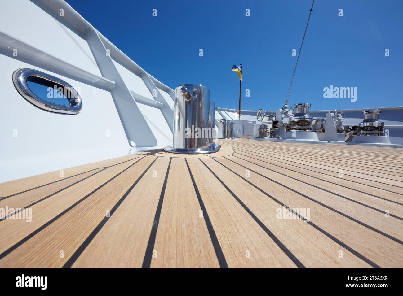 Niedriger Winkel des Teakholzdeckels auf dem Vordeck einer Motoryacht mit Edelstahlklötzen und zwei Ankerwinden. Stockfoto