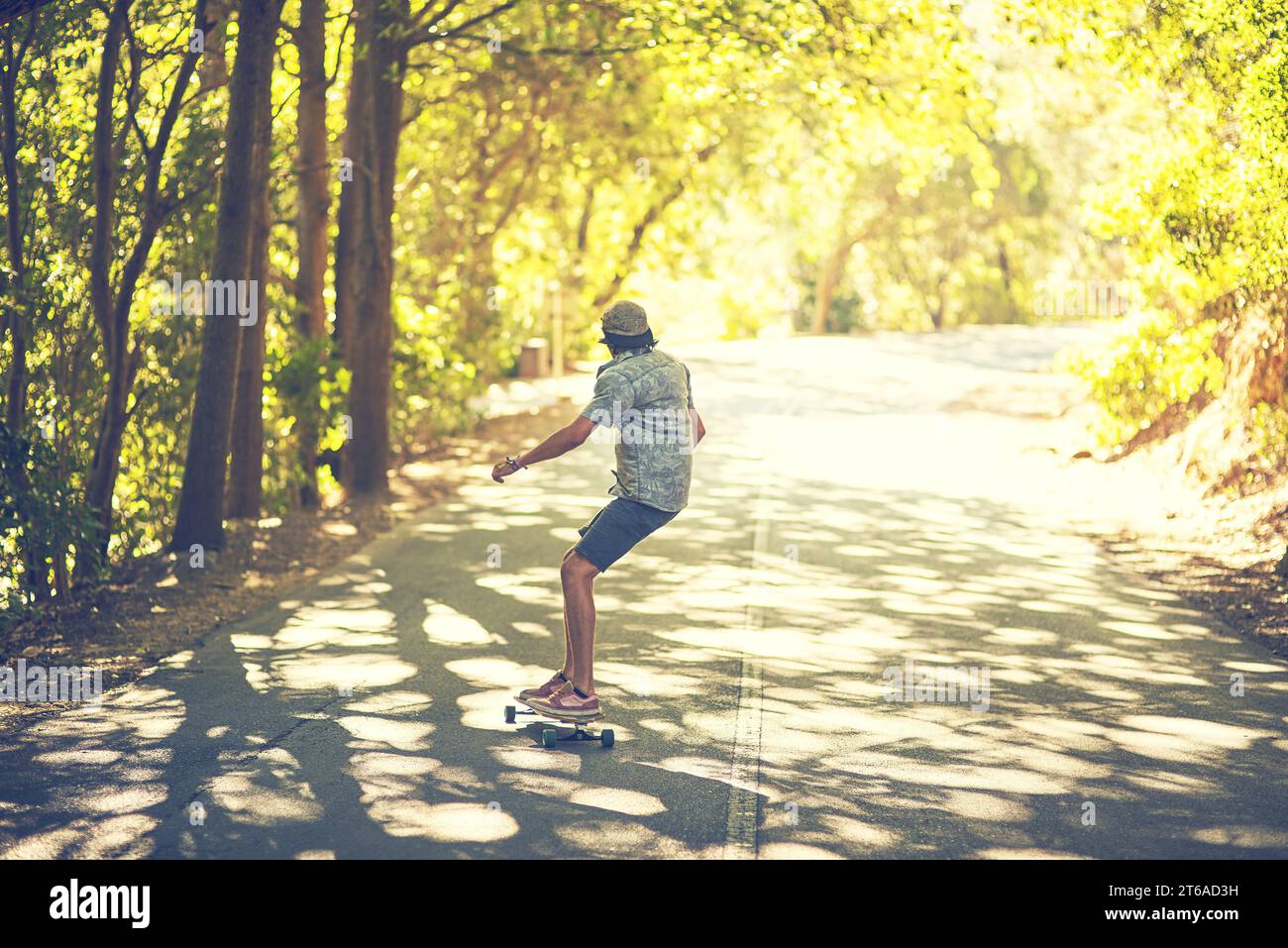 Das Leben eines Skaters ist weit davon entfernt, langweilig zu sein. Rückansicht eines jungen Mannes Longboarding auf der Straße. Stockfoto