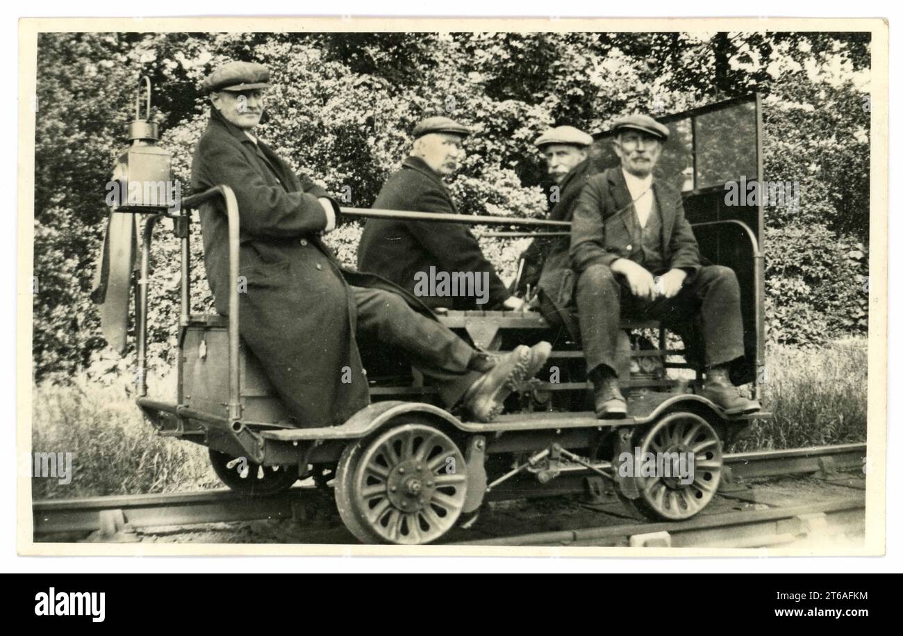 Original-Postkarte aus der Zeit der späten Edwardianer oder frühen 1920er Jahre von 4 Instandhaltungspersonal mit flachen Kappen, die auf einem Eisenbahnwagen sitzen, ein Wagen für die Instandhaltung der Gleise, ein Wagen für die Besatzung, ein Jigger/ein Quad/ein Wagen für die Inspektion, oder Draisine – das waren kleine Triebwagen, die früher weltweit von Gleiskontrolleuren und Arbeitskräften eingesetzt wurden, um schnell zu und von der Baustelle zu fahren. Circa 1927, Großbritannien Stockfoto