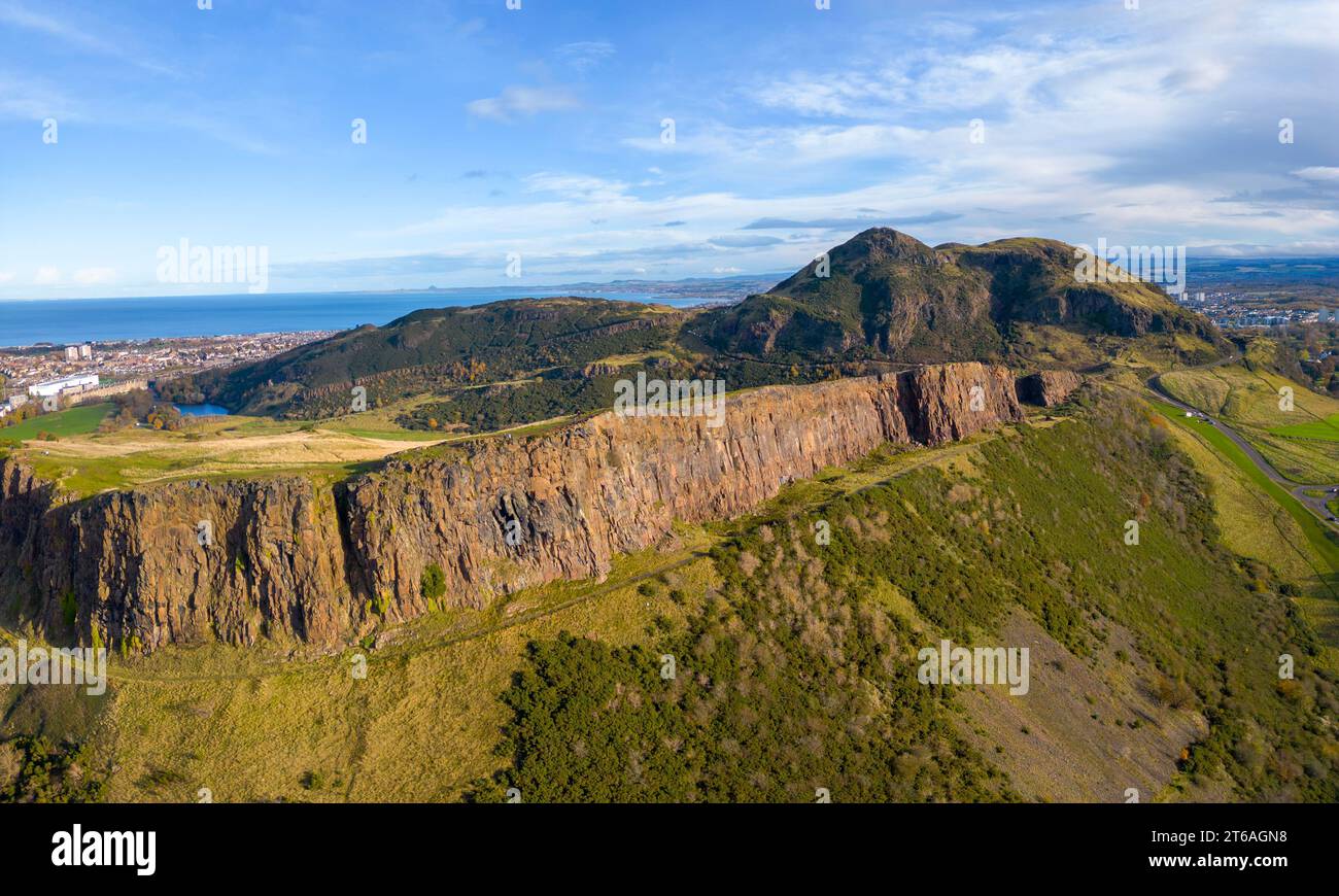 Luftaufnahme der Salisbury Crags mit Arthurs Sitz nach hinten im Holyrood Park, Edinburgh, Schottland, Großbritannien Stockfoto