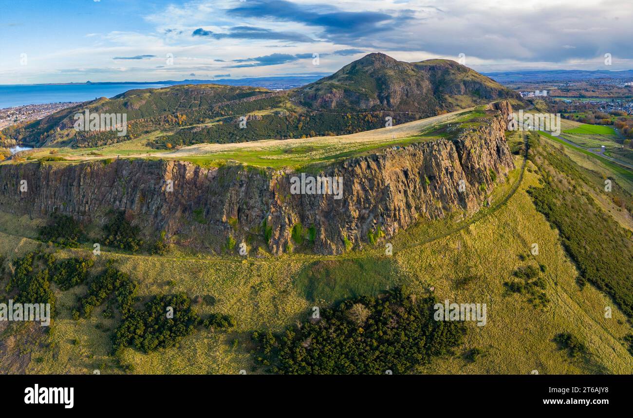 Luftaufnahme der Salisbury Crags mit Arthurs Sitz nach hinten im Holyrood Park, Edinburgh, Schottland, Großbritannien Stockfoto