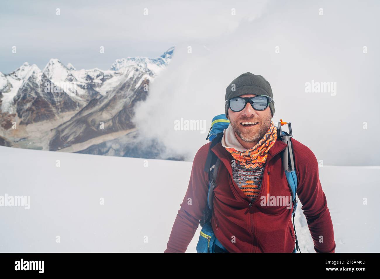 Fröhlicher, lachender Kletterer im Sonnenbrillen-Porträt mit Rucksack, der die hohen Hänge des Mera Gipfels auf 6000 m Höhe ansteigt und den legendären Mount Everest, Nuptse und Lhot genießt Stockfoto