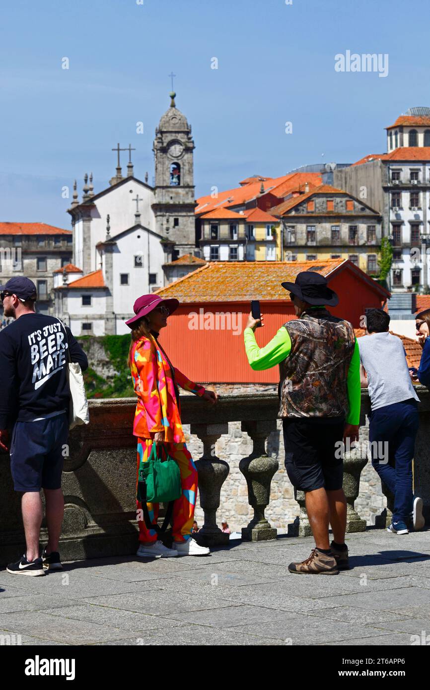 Ein weiblicher Tourist lässt sich auf der Terreiro da Sé-Terrasse, Nossa Senhora da Vitoria-Kirche im Hintergrund, Porto/Porto, Portugal, fotografieren Stockfoto