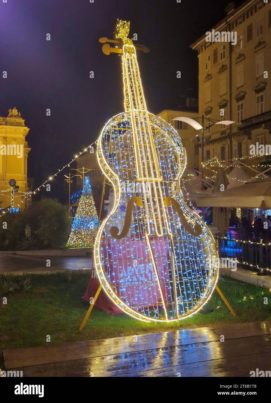 Neujahr- und Weihnachtslichtinstallation in Form eines Cello und Weihnachtsbeleuchtung im Park. Beleuchtete Geigenform in der Weihnachtszeit. Stockfoto