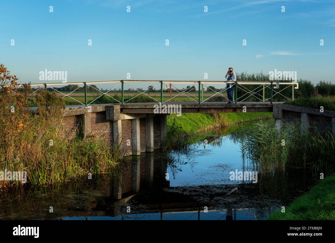 Noorddijk, Groningen, 10-20-2018. Ein Fotograf auf der Brücke über den Zuidwendinger Kanal in Noorddijk am Stadtrand von Groningen. Stockfoto