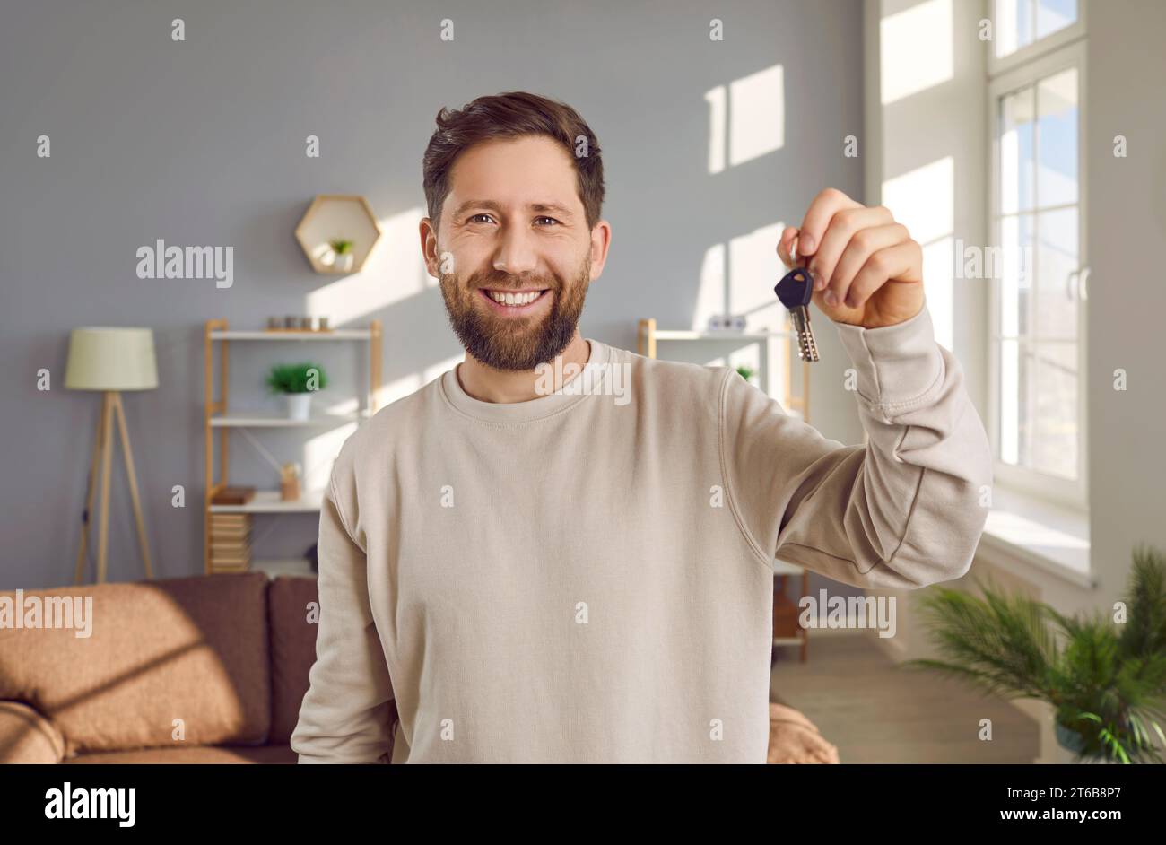 Porträt eines jungen, fröhlich lächelnden, attraktiven Mannes mit Schlüsseln in der Hand. Stockfoto