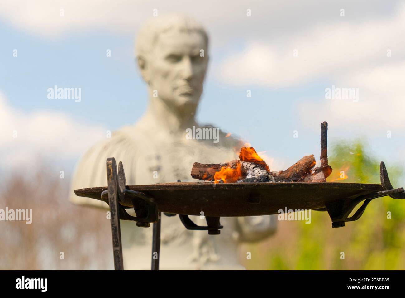 Antike römische Opferfeuer für die römischen Götter mit einer römischen Statue im Hintergrund. Stockfoto
