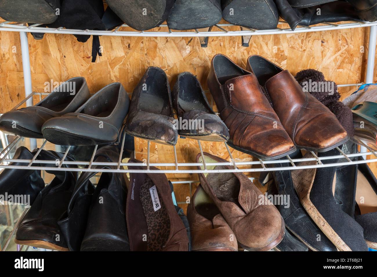 Metallregal mit gebrauchten Damenschuhen zum Verkauf im Gebrauchtwarenladen. Stockfoto