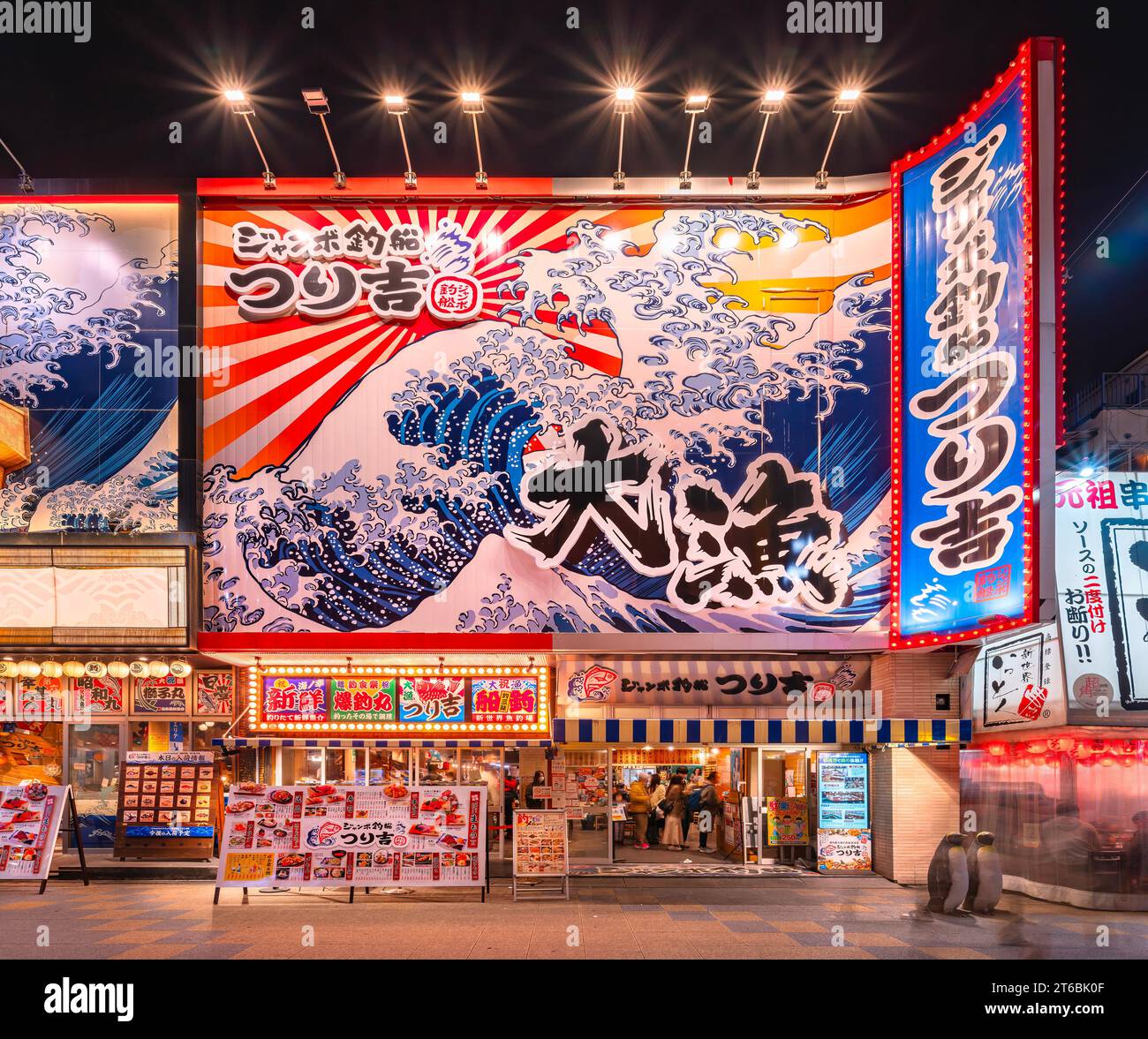 osaka, japan - 04. dezember 2022: Fisch- und Meeresfrüchterestaurant Jumbo Tsuribune Tsurikichi mit einem riesigen Plakat an der Fassade, das Meereswellen darstellt Stockfoto