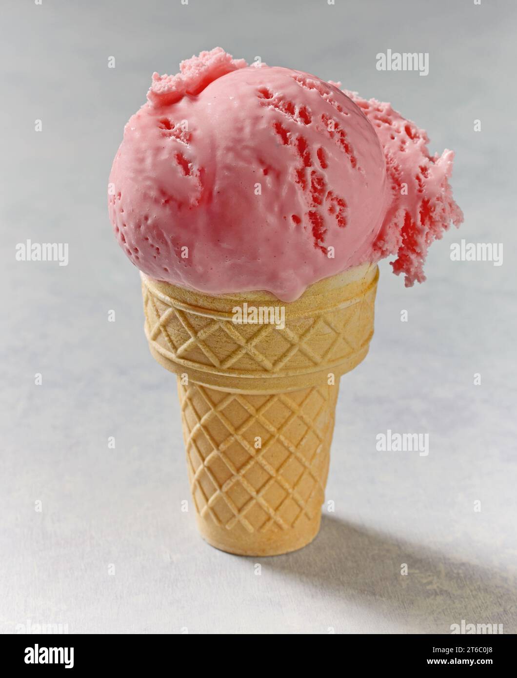 Rosafarbenes Eis in Waffelkegel auf einem Tisch Stockfoto