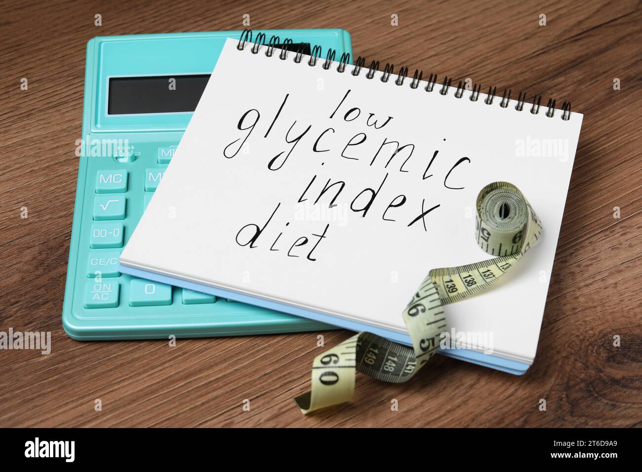 Notizbuch mit den Worten Low glycemic Index Diät, Maßband und Taschenrechner auf Holztisch Stockfoto