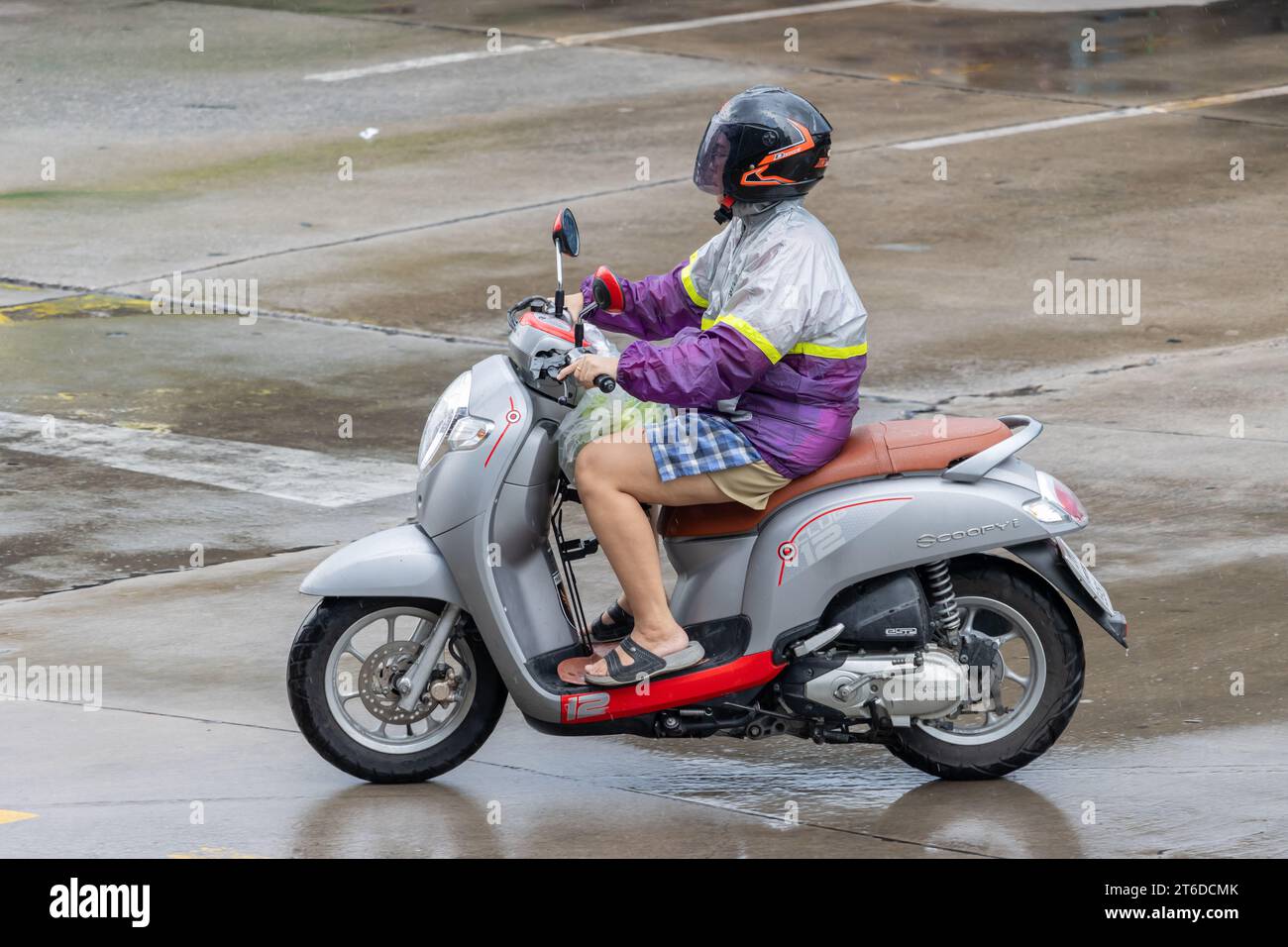 SAMUT PRAKAN, THAILAND, 13. Oktober 2023, Eine Frau fährt bei Regen Motorrad auf der Straße. Stockfoto