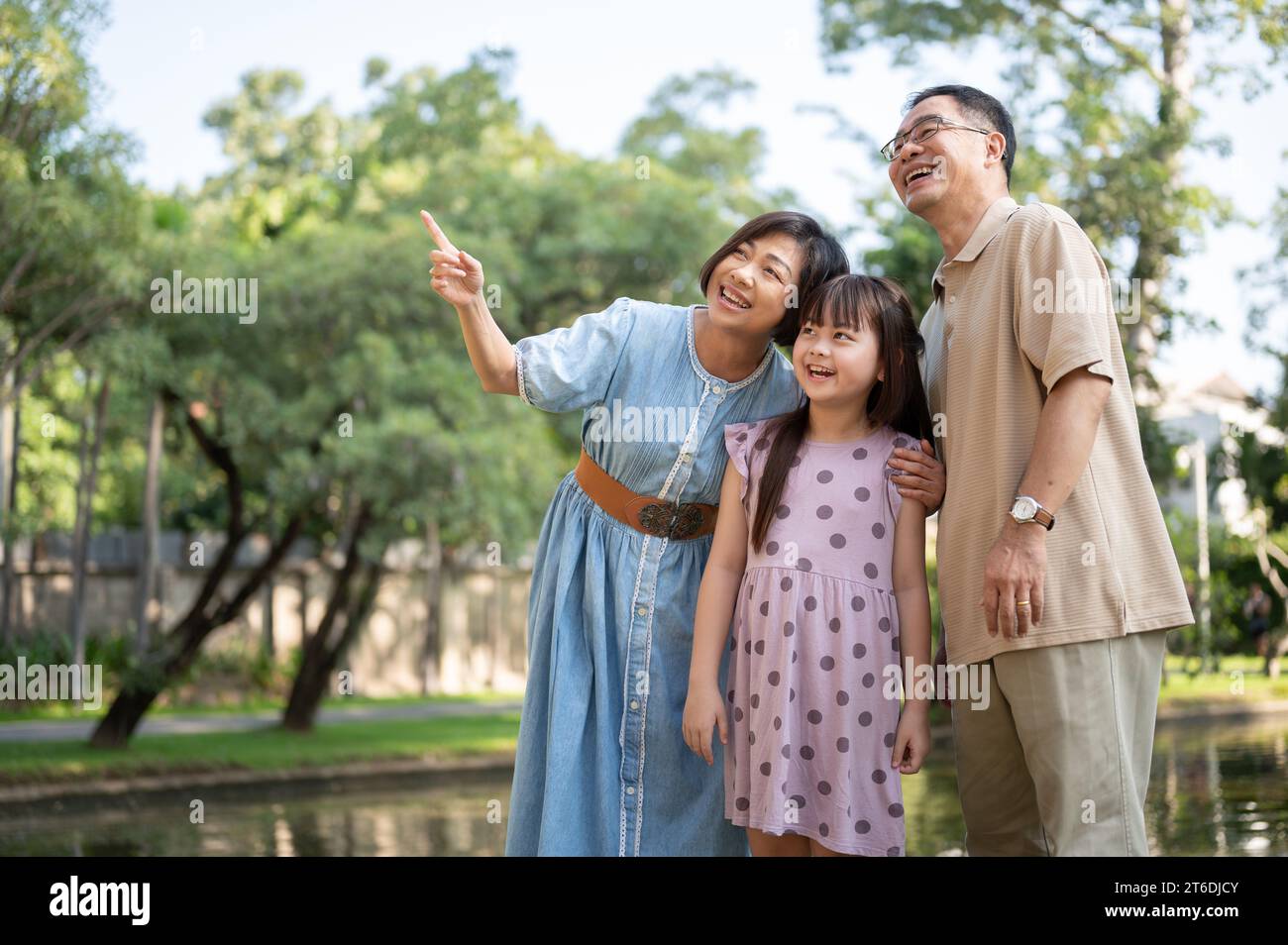 Nette und glückliche asiatische Großeltern haben Spaß mit ihrer Enkelin und schlendern an einem hellen Tag gemeinsam durch den öffentlichen Park. Glückliche Familie, fa Stockfoto