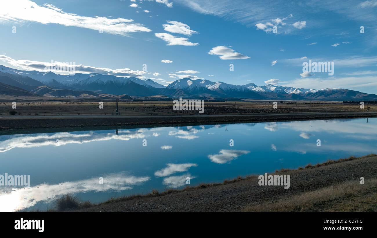 Aus der Vogelperspektive des Pukaki-Wasserkraftkanals im ländlichen Twizel, der parallel zum heute bedeckten Ben Ohau-Gebirge verläuft Stockfoto