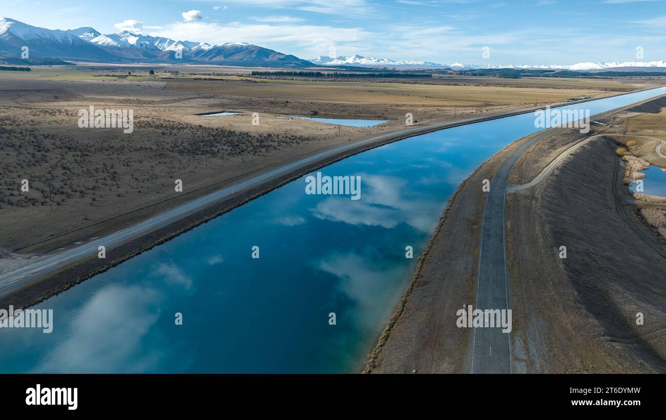 Aus der Vogelperspektive des Pukaki-Wasserkraftkanals im ländlichen Twizel, der parallel zum heute bedeckten Ben Ohau-Gebirge verläuft Stockfoto