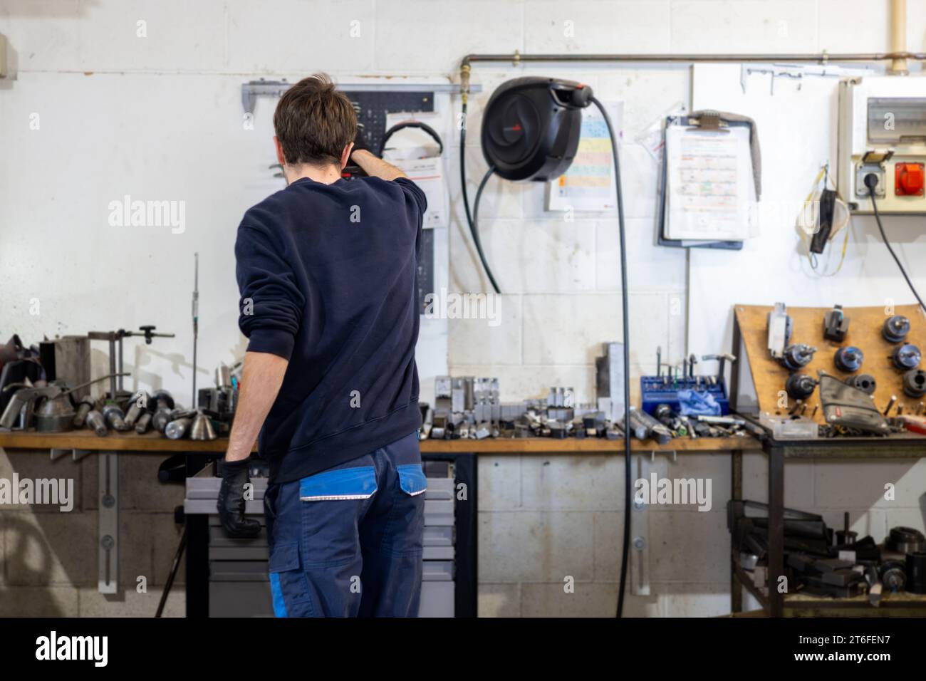 Junger professioneller Mann, der in einer Metallwerkstatt arbeitet. Industriemechaniker und Fahrzeugreparaturen. Stockfoto