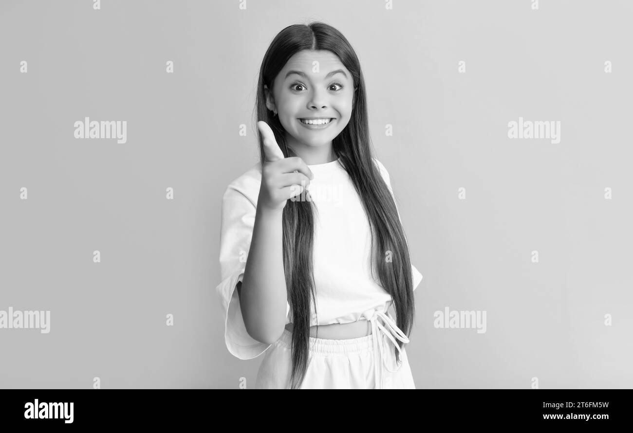 Stauntes Kind mit langem Haar, das mit dem Finger auf blauem Hintergrund zeigt, Werbung. Stockfoto