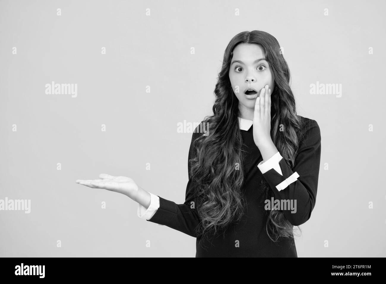 Überrascht Emotionen der jungen Teenager-Mädchen. Nahaufnahme Porträt eines Teenagers Kind Mädchen zeigt auf Kopieplatz, zeigt auf Anzeigen Werbung, isoliert über Stockfoto