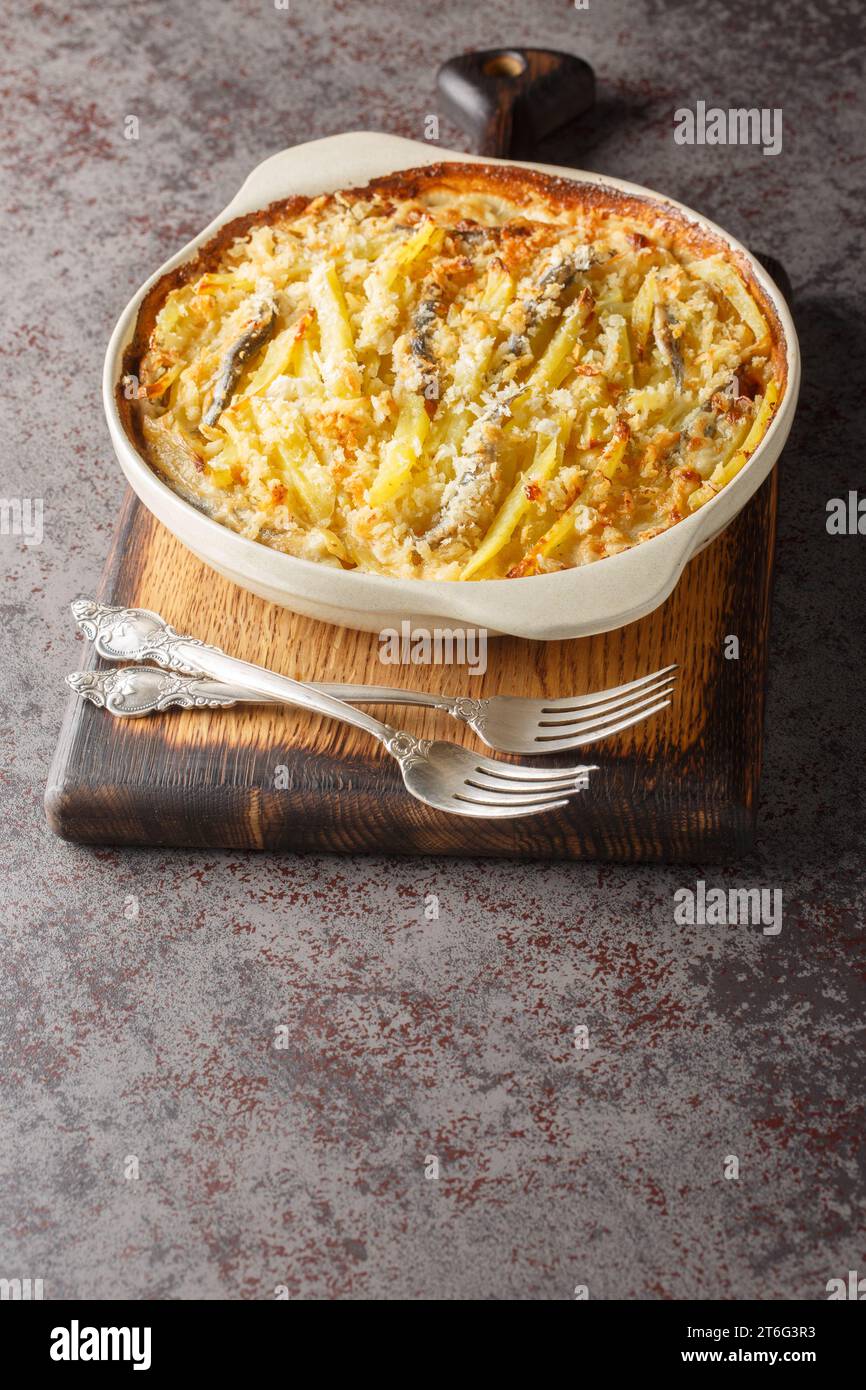 Janssons frestelse-Auflauf besteht aus Kartoffeln und Sardellen, die mit Zwiebeln überlagert und dann in Creme-Nahaufnahme auf der Auflaufform auf t übergossen werden Stockfoto