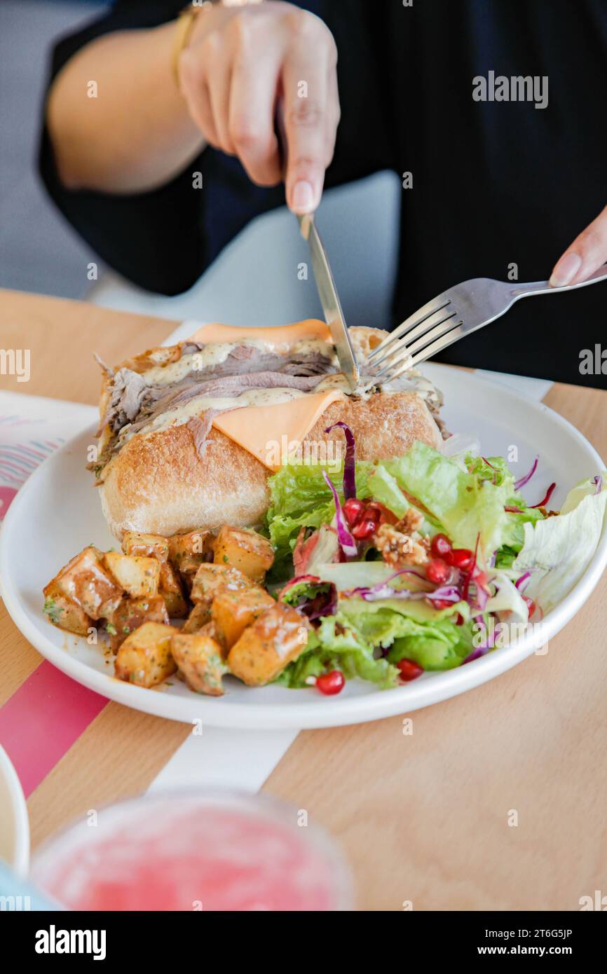 Eine Person, die Roastbeef mit offenem Gesicht Sandwich mit Gemüse auf der Seite hat. Stockfoto