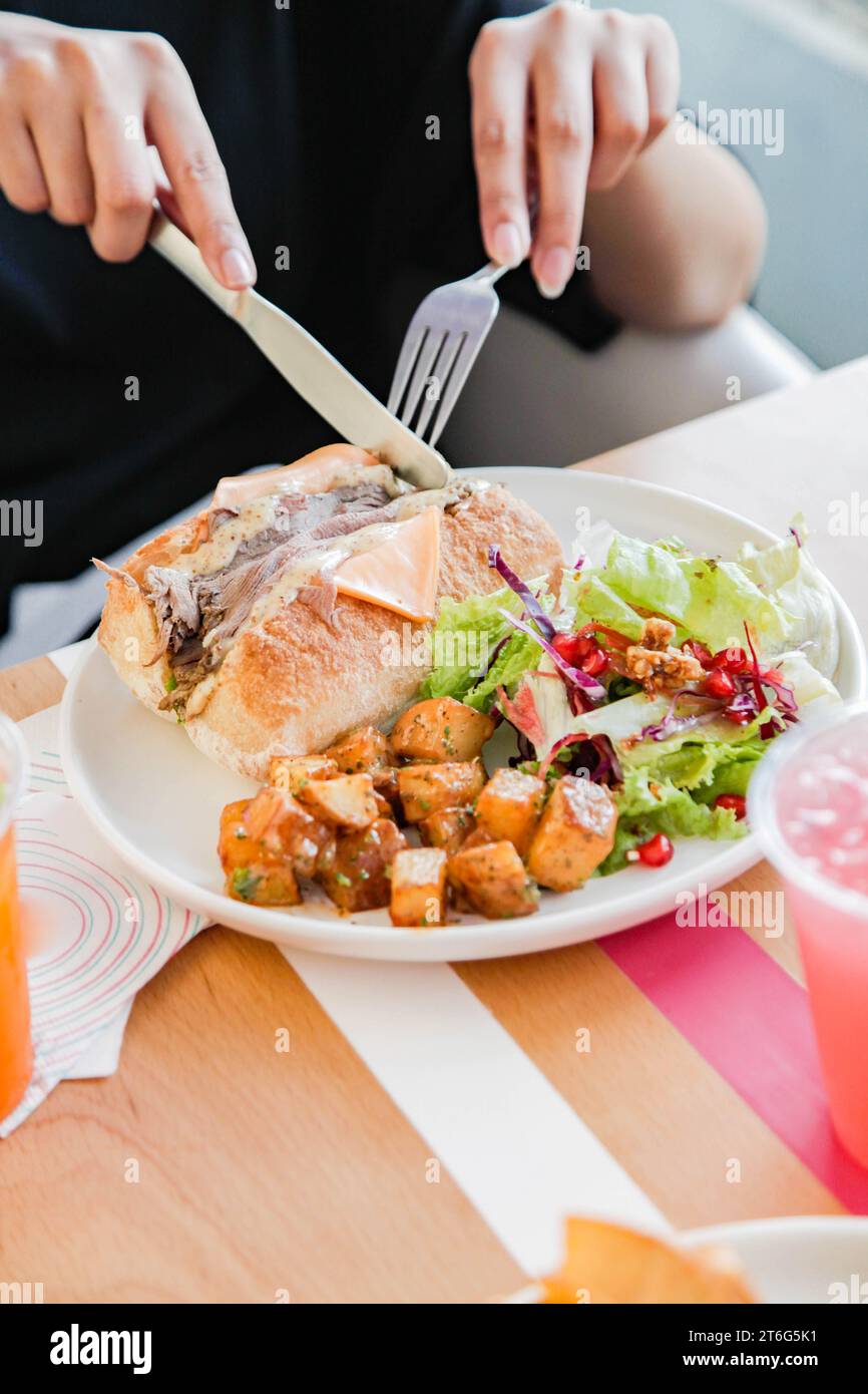 Eine Person, die Roastbeef mit offenem Gesicht Sandwich mit Gemüse auf der Seite hat. Stockfoto