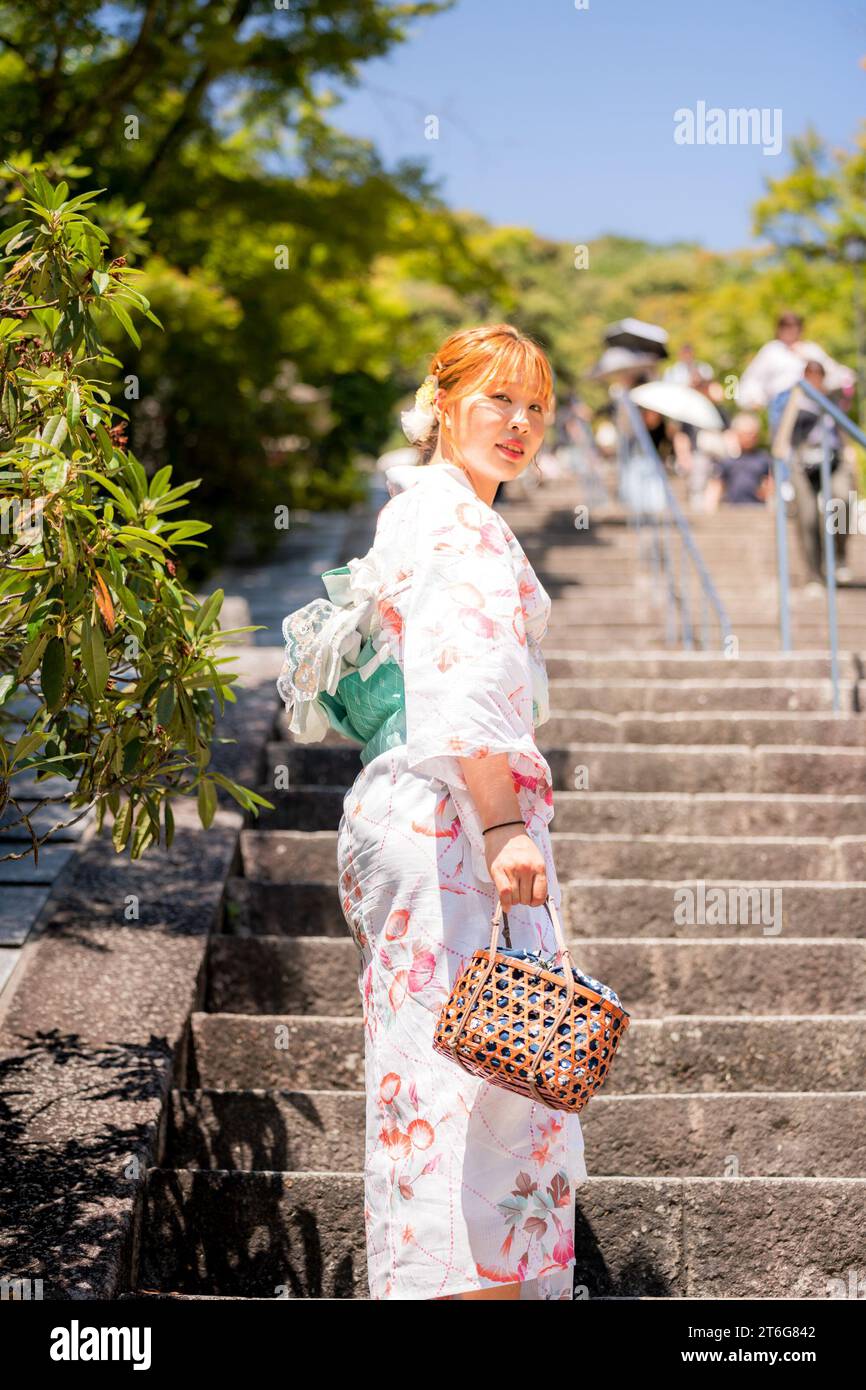 Porträt einer jungen Frau mit japanischem Yukata-Sommerkimono, die auf der Steintreppe steht. Kyoto, Japan. Stockfoto