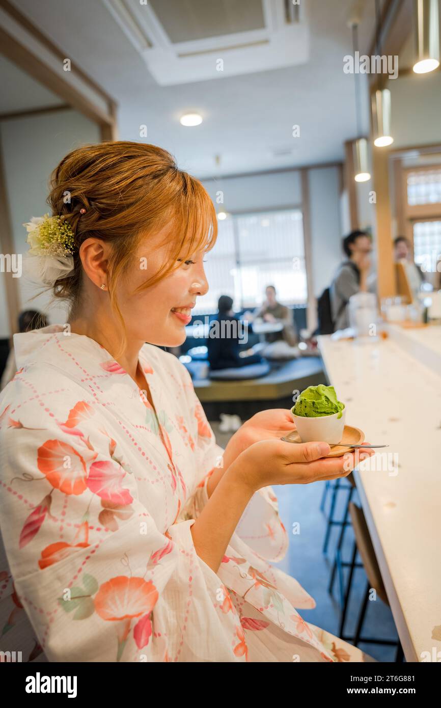 Porträt einer jungen Frau mit japanischem Yukata-Sommer-Kimono und Matcha-Eis in einem Teeladen. Kyoto, Japan. Stockfoto