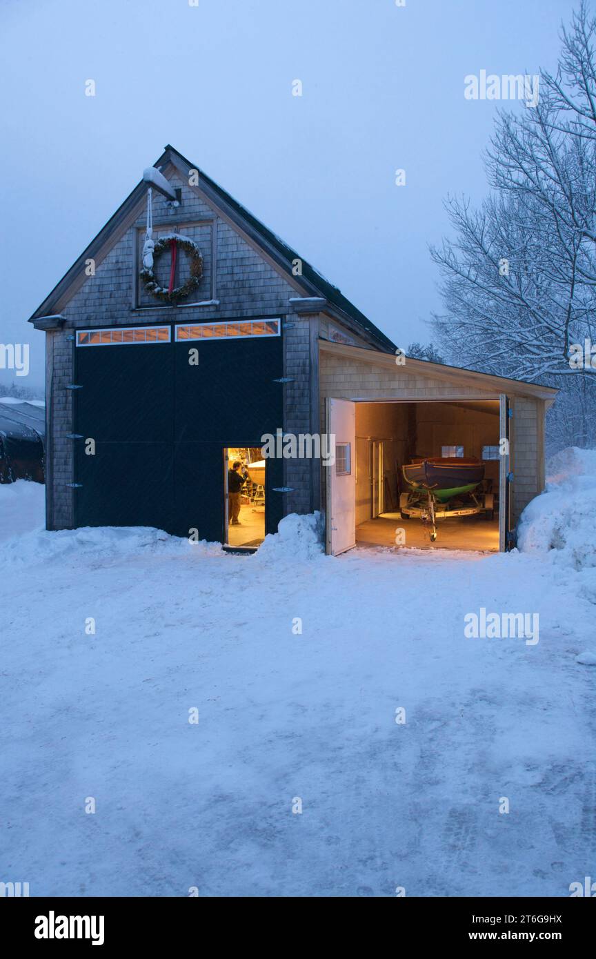 Ein schneebedeckter Blick auf einen Bootsbauer durch die offene Schuppentür. Stockfoto
