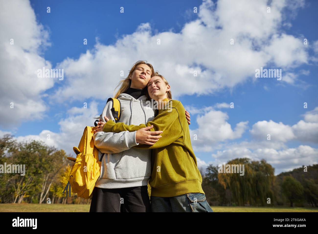 Junge Mädchen stehen umarmt vor dem Himmel Stockfoto