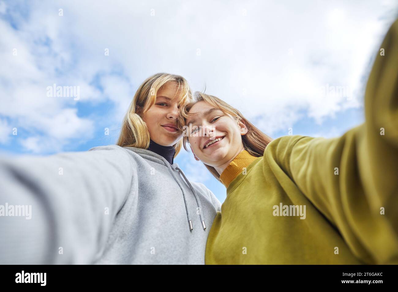 Zwei junge Mädchen posieren für ein Selfie gegen den Himmel Stockfoto