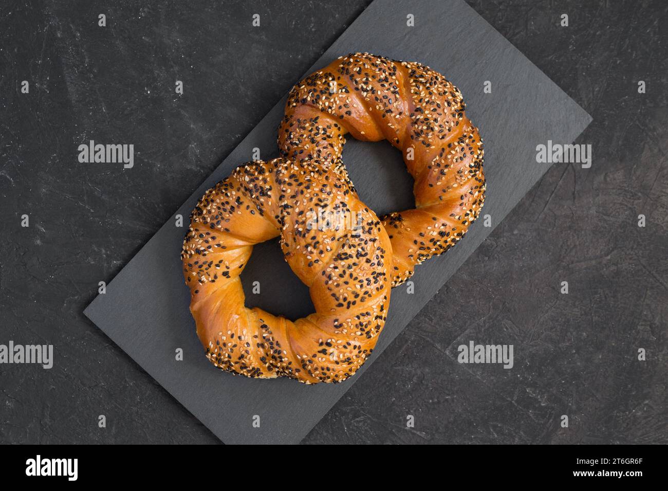 Leckere frisch geröstete Bagels, bestreut mit weißen und schwarzen Sesamsamen auf dunklem Hintergrund. Türkische Bagels oder Simits - traditionelle Bäckerei. Draufsicht, Stockfoto