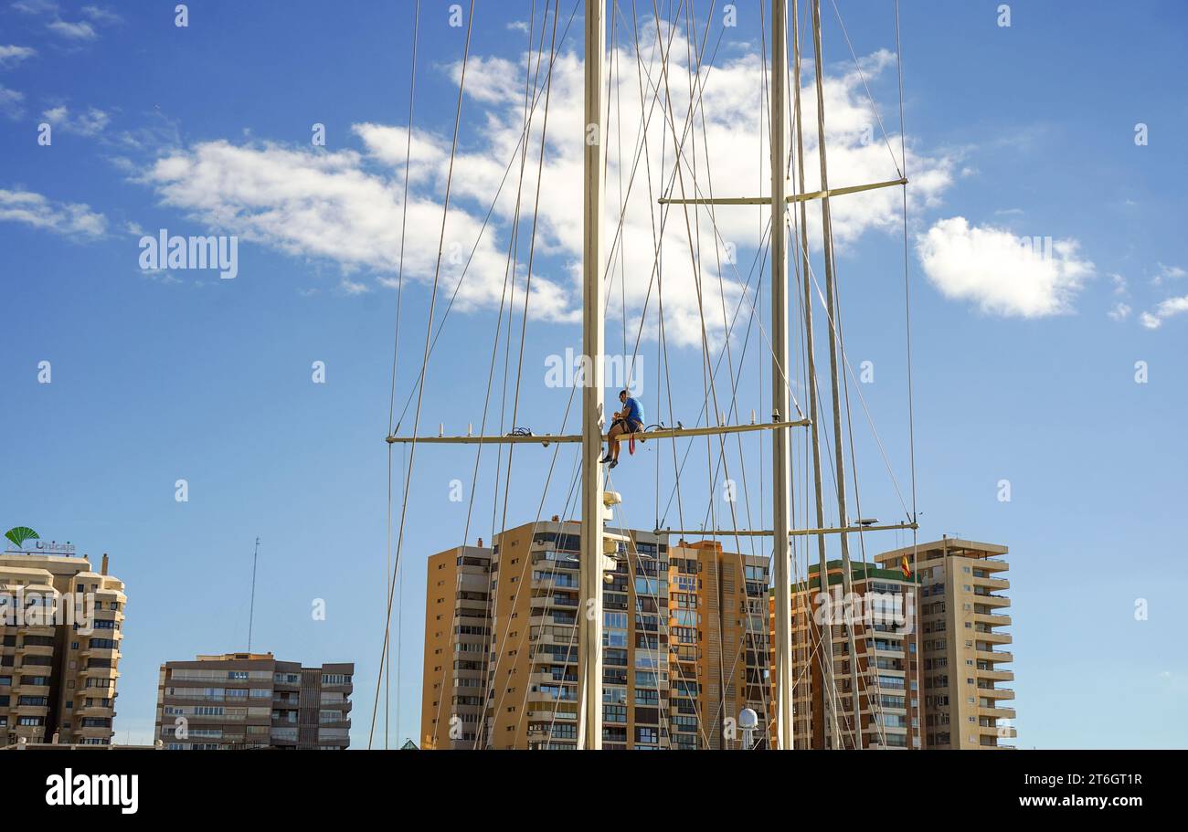 Mann, der hoch im Mast eines Segelschiffes arbeitet, Malaga, Spanien. Stockfoto