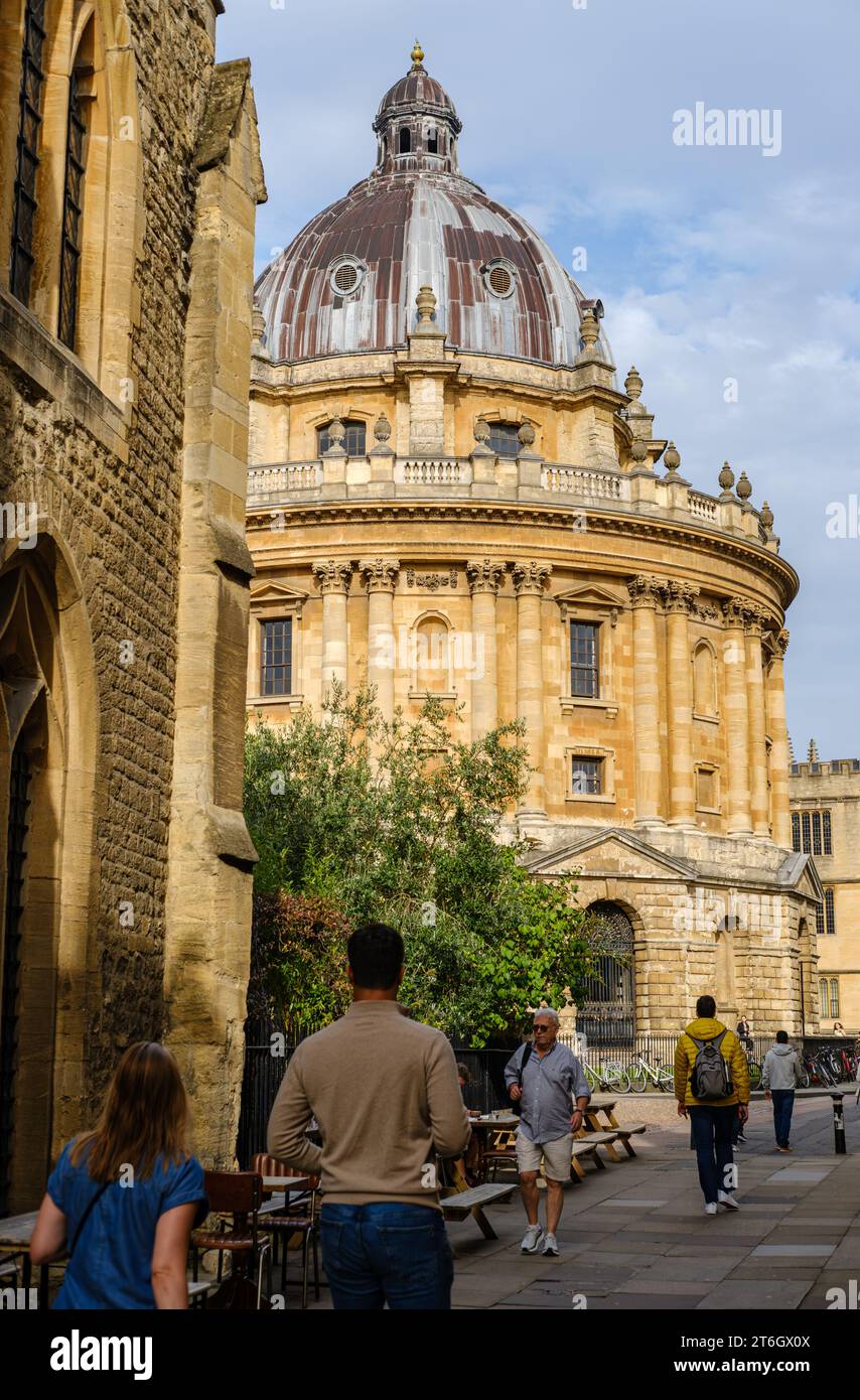 Leute, die in Catte Street, Oxford, England, Großbritannien, mit der Radcliffe Camera und Bodleian im Hintergrund unterwegs sind Stockfoto