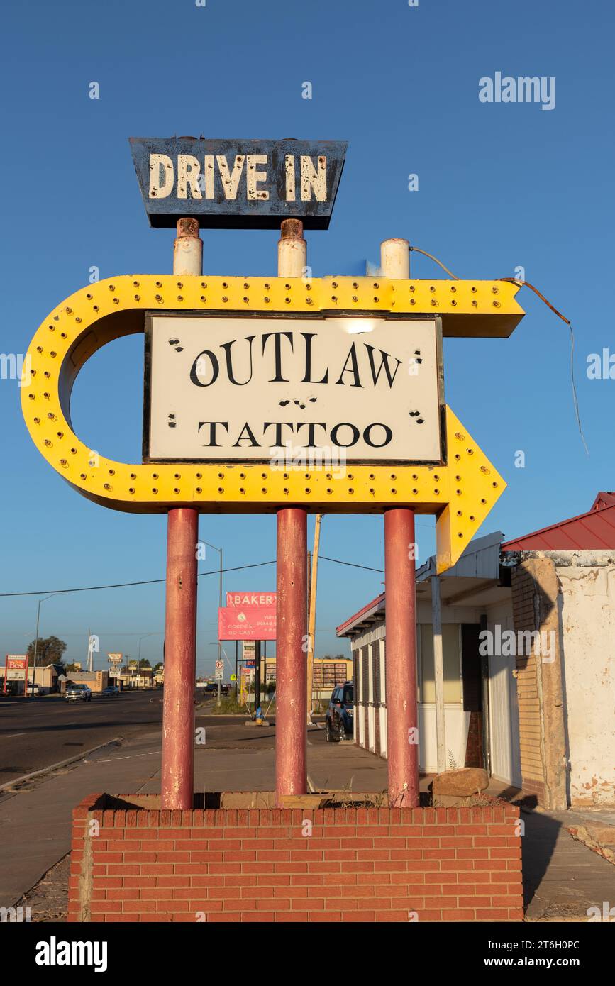 Schild, mit großem gelben Pfeil, für Drive in Outlaw Tattoo, nicht mehr im Geschäft, Tucumcari, New Mexico, USA. Stockfoto