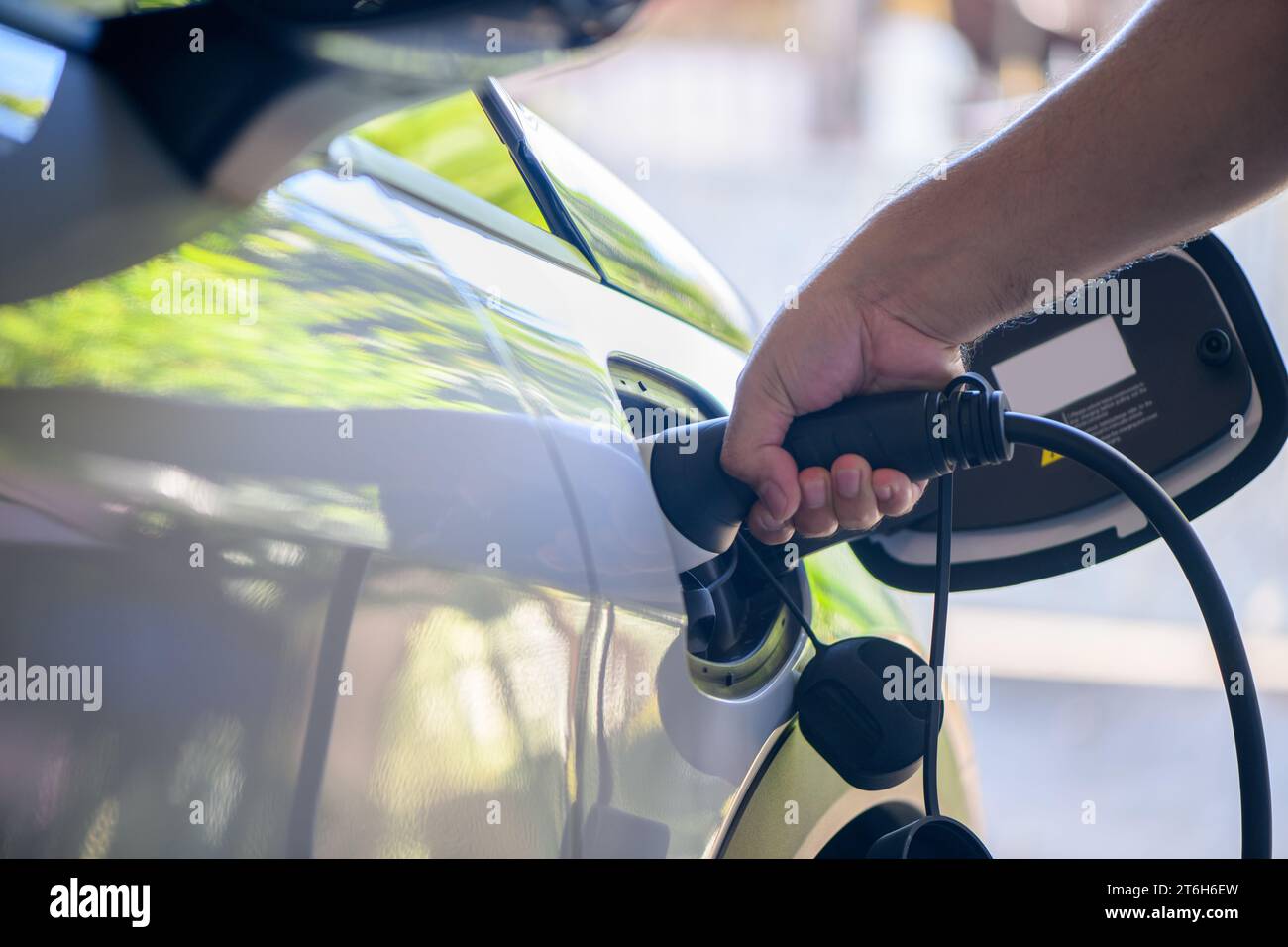 Man steckte Stecker Ladekabel Elektrofahrzeug. Der Fahrer entfernt das Ladegerät seines Elektrofahrzeugs. Umwelt und alternative Energie nachhaltig der Zukunft sparen Stockfoto