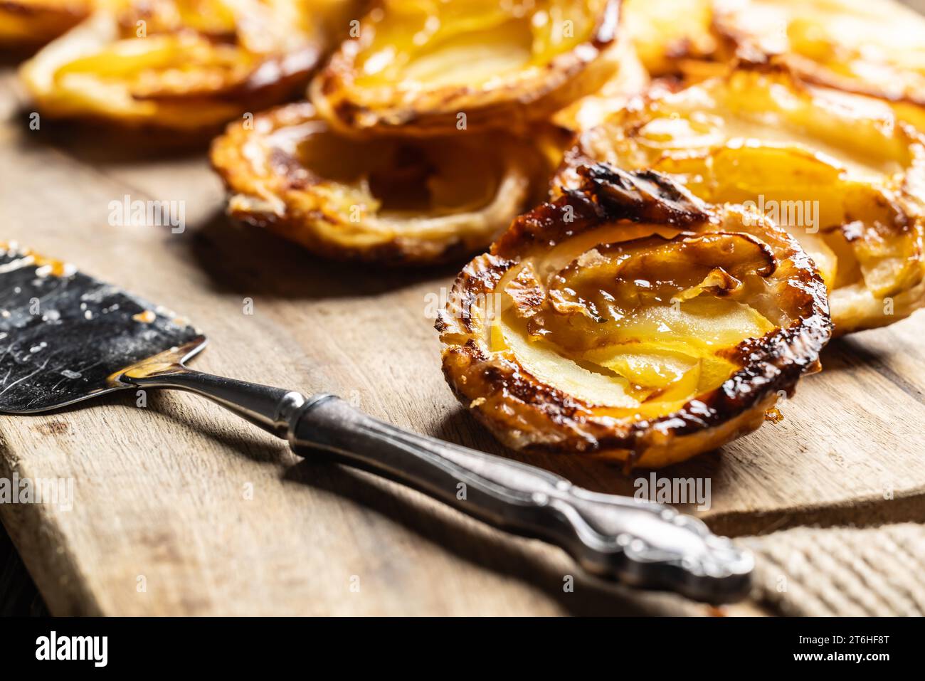 Mini-Torten aus Blätterteig und geschnittenen Äpfeln auf einem Schneidebrett. Frankreich Apfelkuchen - Nahaufnahme. Stockfoto