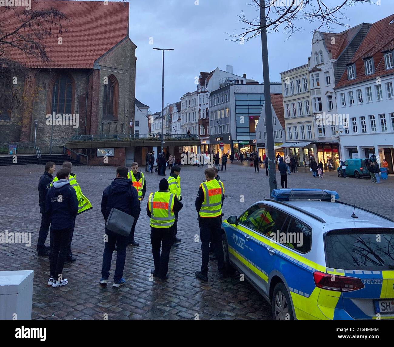 Flensburg, Schleswig-Holstein, Poizisten und Mitarbeiter des Ordnungsamtes Flensburg i. BI. Vorne sichern eine Mahnhwache. Die Personen B. mitte halten schwarzes Transparent vor mit Aufschrift Shell to Hell. In Gedenken an die Ogoni 9 Umweltaktivisten dann die Namen die am 10.11.1995 im auftrag von Shell erhängt wurden. Aufnahme vom 10.11.2023, Flensburg, Südermarkt *** Flensburg, Schleswig Holstein, Polizeibeamte und Mitarbeiter des Ordnungsamtes Flensburg i BI sichern vorne eine Mahnwache die Leute B in der Mitte halten ein schwarzes Banner mit der Aufschrift Shell to hell zum Gedenken an den Stockfoto