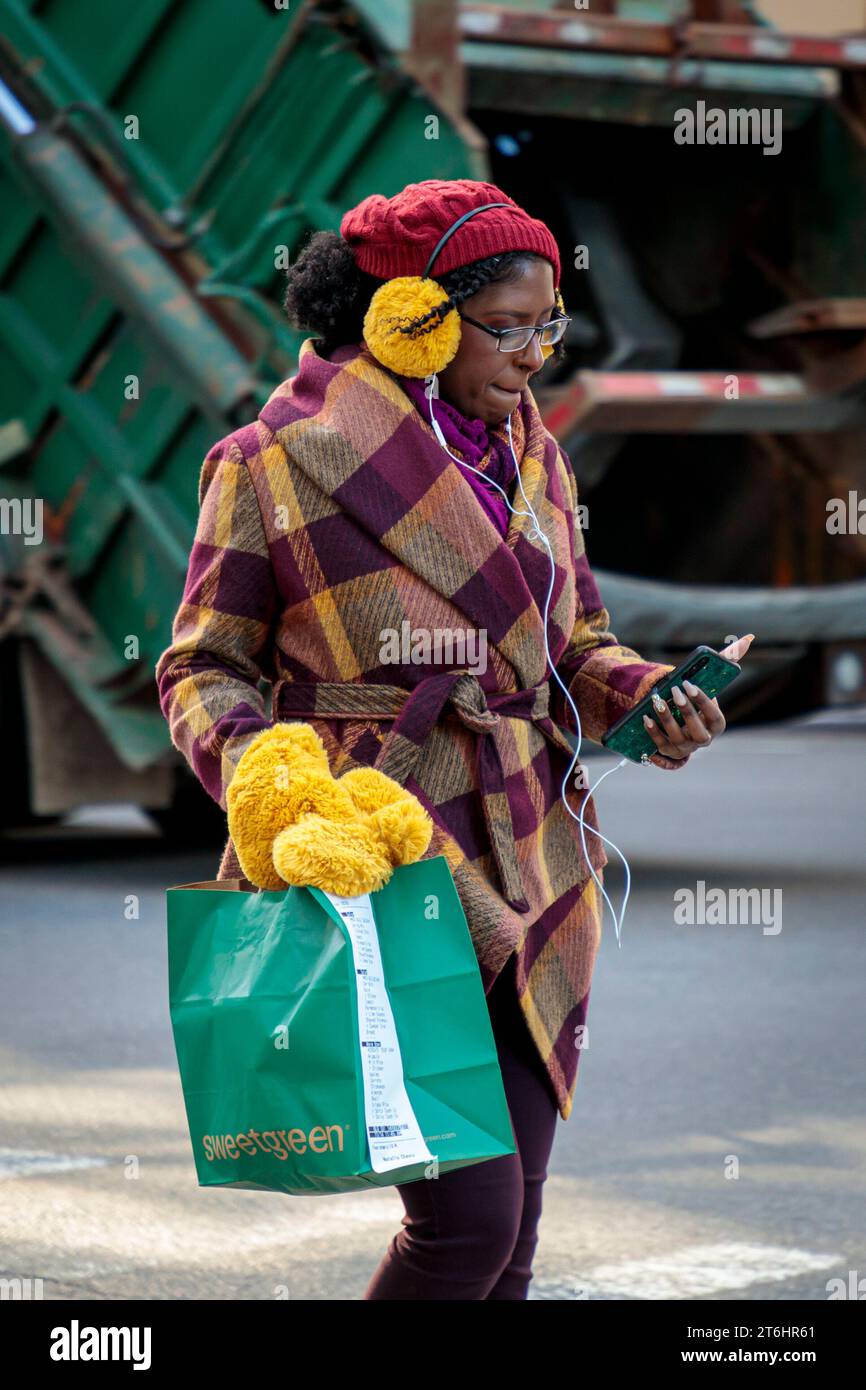 Junge modische Frau, die Musik hört, während sie eine Straße überquert, Manhattan, New York City, Nordamerika, USA, USA Stockfoto